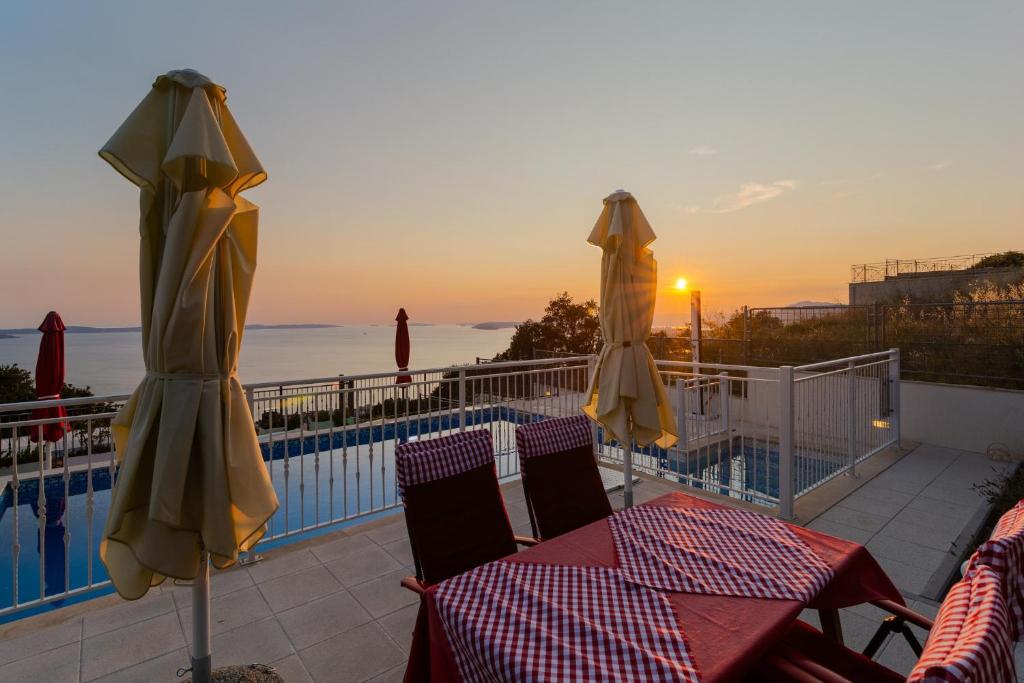 zwei Tische und Sonnenschirme auf einem Balkon mit Pool in der Unterkunft Kuća za odmor R&A in Podstrana