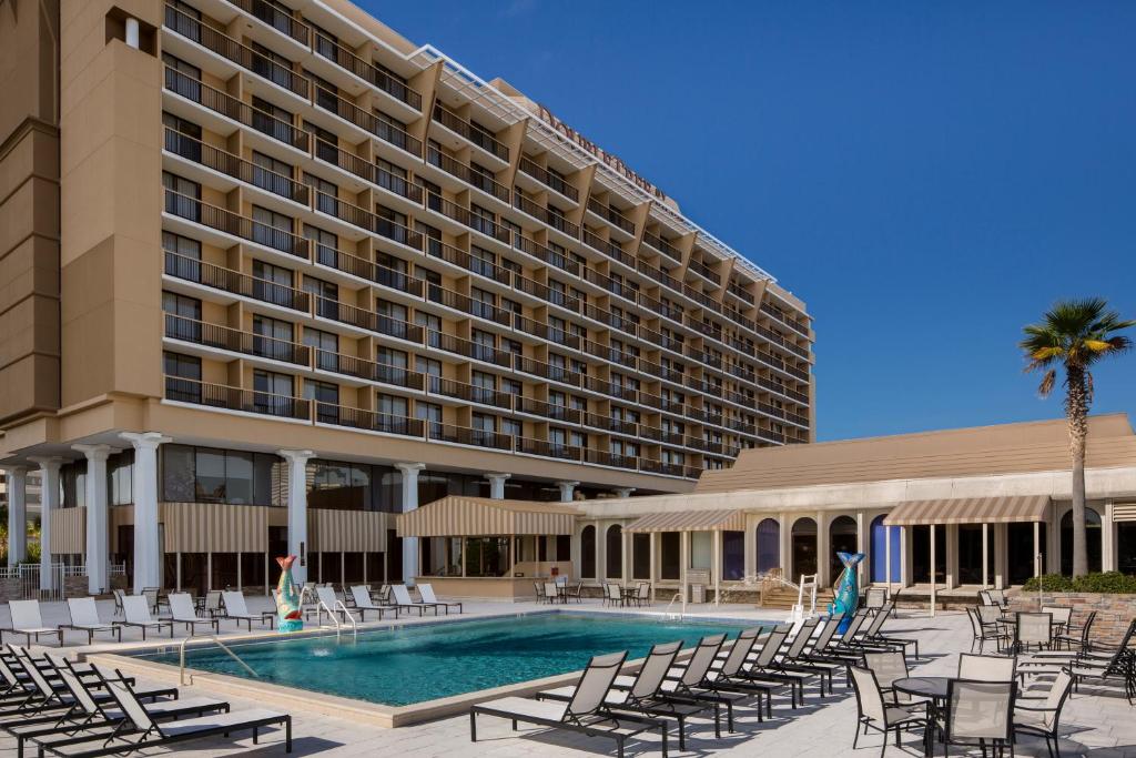 a hotel with a pool and chairs and a building at DoubleTree by Hilton Hotel Jacksonville Riverfront in Jacksonville
