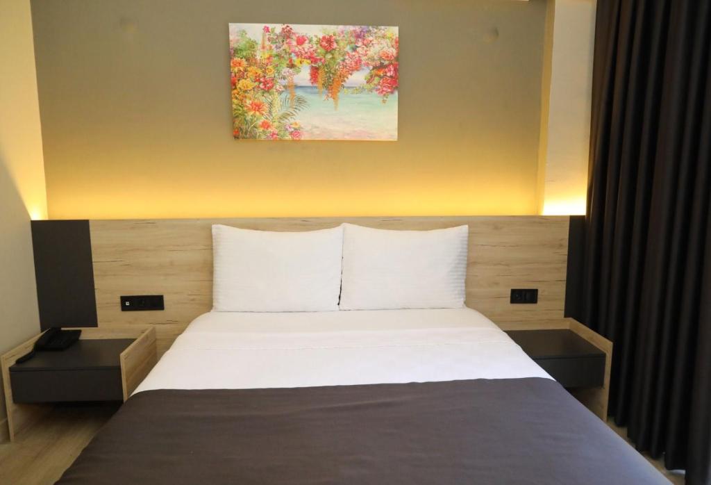 a bedroom with a bed with a painting on the wall at Grand Faik Hotel in Çeşme