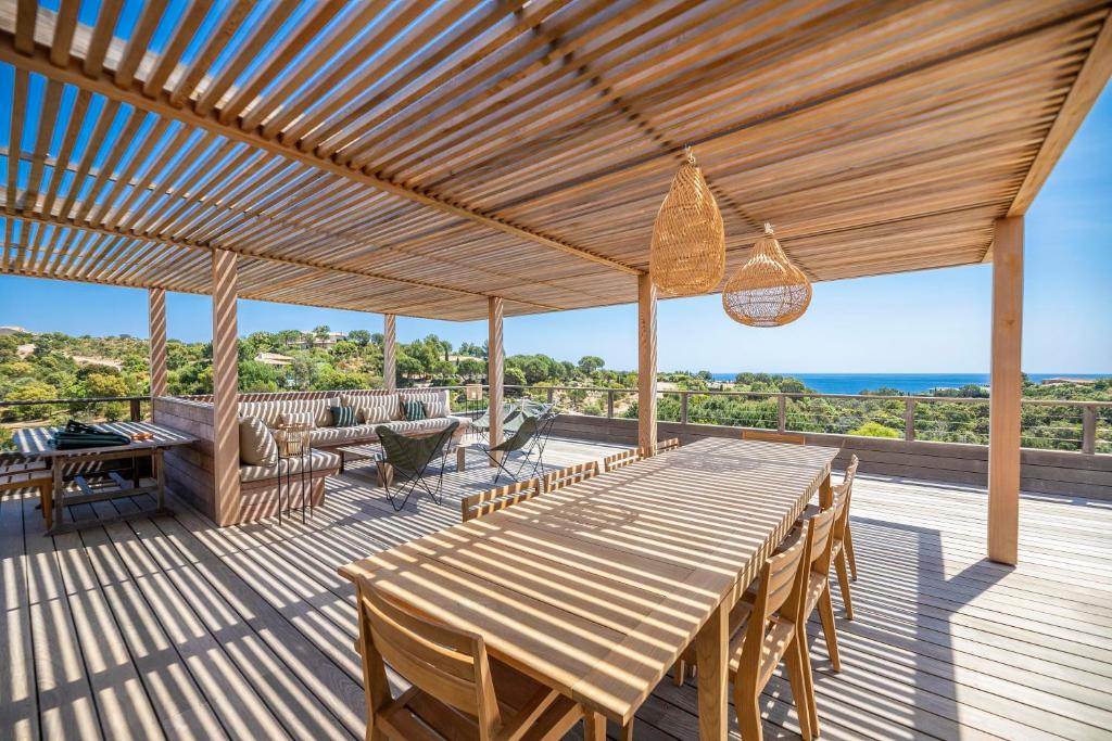 une terrasse en bois avec une table et des chaises en bois dans l'établissement Superbe Villa Porto Vecchio vue mer plage à pied, à Porto-Vecchio
