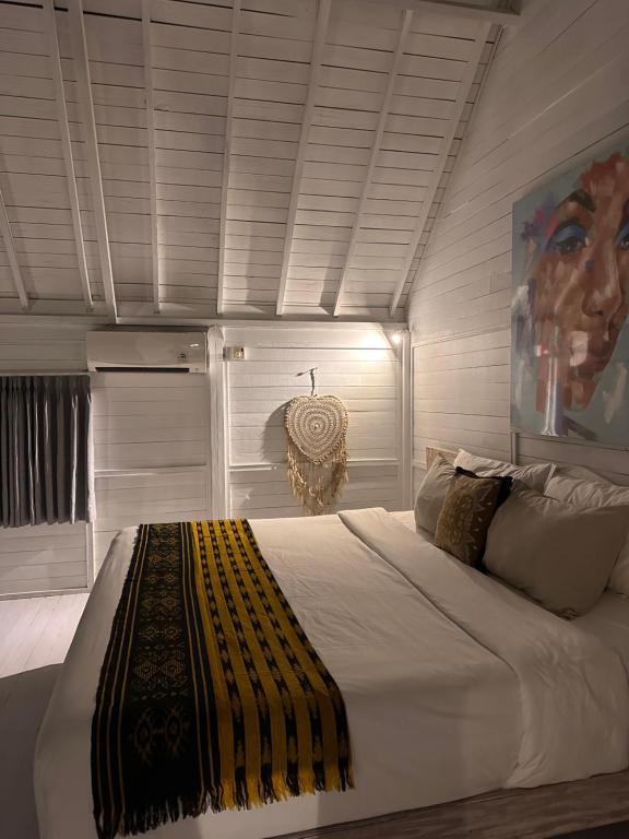 a bedroom with a large white bed with a yellow blanket at Kenzo hut3 mesari in Seminyak