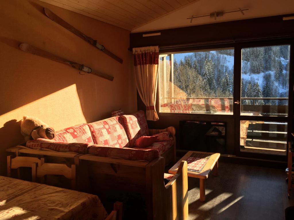 un salon avec un canapé, une table et une fenêtre dans l'établissement Splendide vu sur les ARAVIS, à La Clusaz