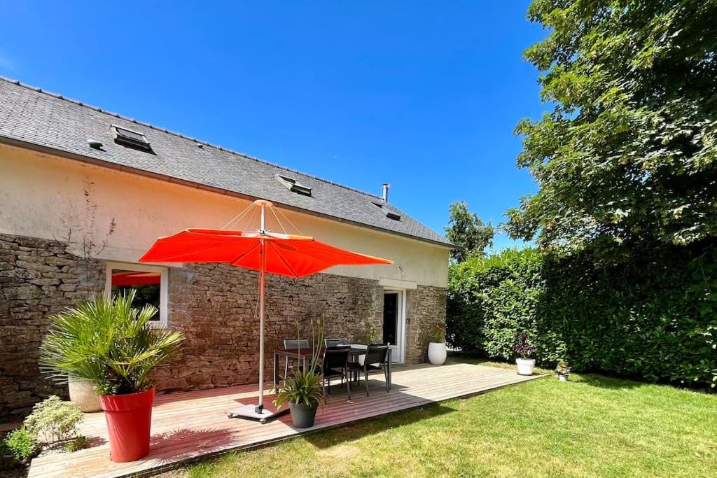 une terrasse avec un parasol rouge, une table et des chaises dans l'établissement LE GITE DE SOANI avec terrasse & jardin, à Saint-Évarzec