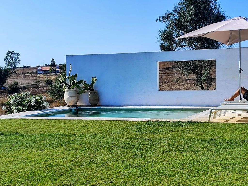 Una piscina en un patio con una sombrilla. en Casa dos Bonitos, en Santa Susana