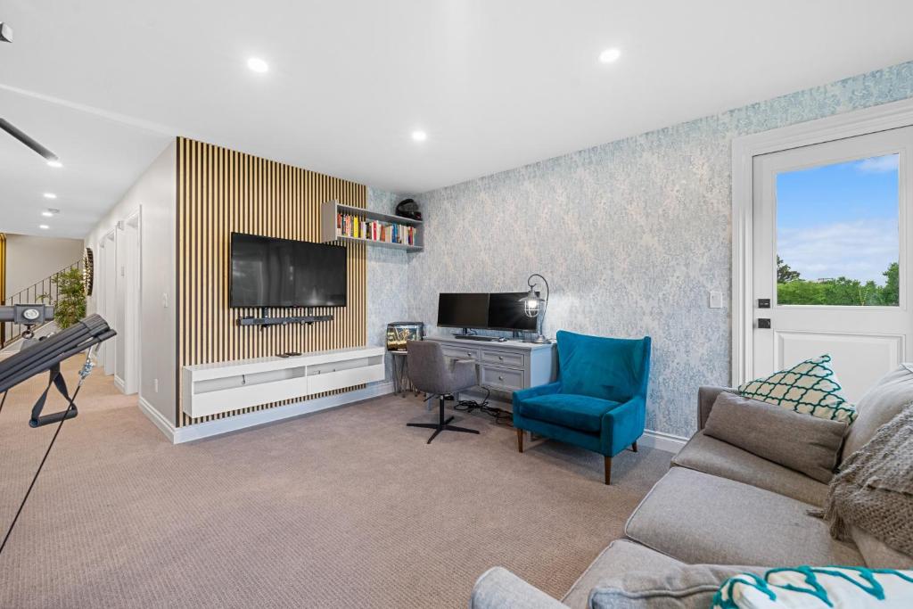 a living room with a tv and a blue chair at Casa Ladrillo - House of Bricks in Calgary