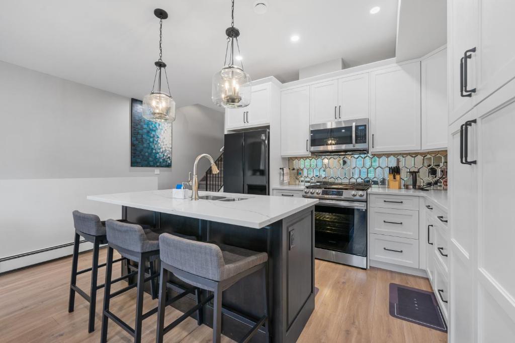 a kitchen with white cabinets and a kitchen island with bar stools at Casa Ladrillo - House of Bricks in Calgary