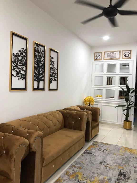 a living room with two brown couches and a ceiling fan at Ammara Homestay PD in Kampong Tanah Merah