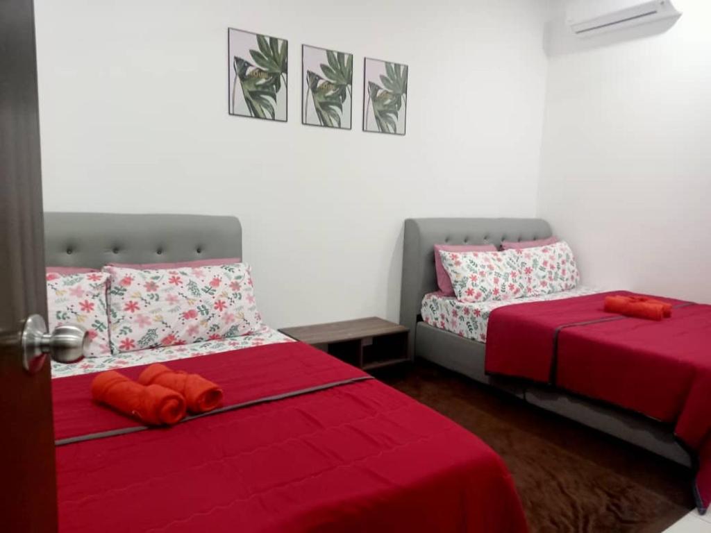 a bedroom with two beds with red sheets and a red pillow at Ammara Homestay PD in Kampong Tanah Merah