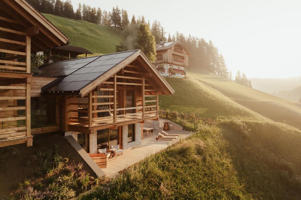 a log cabin on a hill with a house at Lominus Dolomites Luxury Chalet for 2 in San Martino in Badia