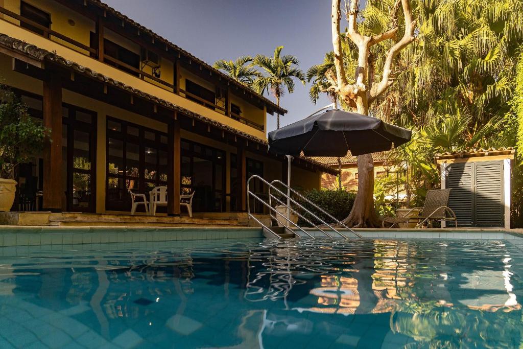 ein Swimmingpool mit Sonnenschirm neben einem Gebäude in der Unterkunft Casa Omegna in São Sebastião