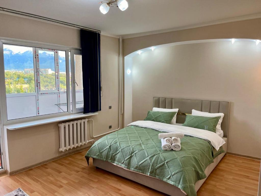 a bedroom with a bed with a large window at sairan comfort in Almaty