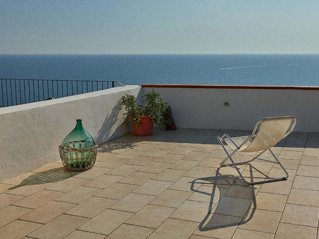 ein Stuhl und eine Vase auf einem Balkon mit Blick auf das Meer in der Unterkunft La Ripa-apartment on the cliff edge in Peschici