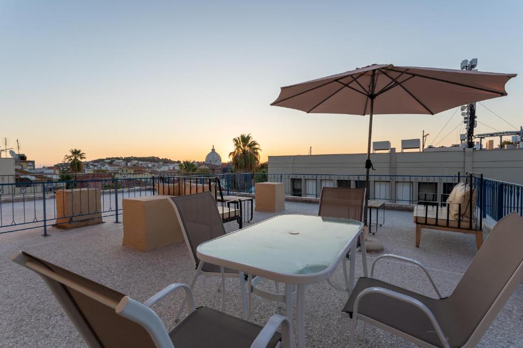 a table and chairs with an umbrella on a roof at Central Mytilene City-View Apartment for 7 in Mytilini