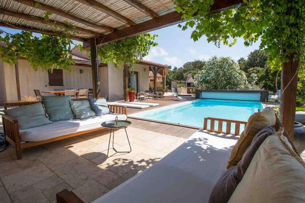 une terrasse avec un canapé et une piscine dans l'établissement villa soleluna, villa de charme, lumineuse et cosy, à Bonifacio