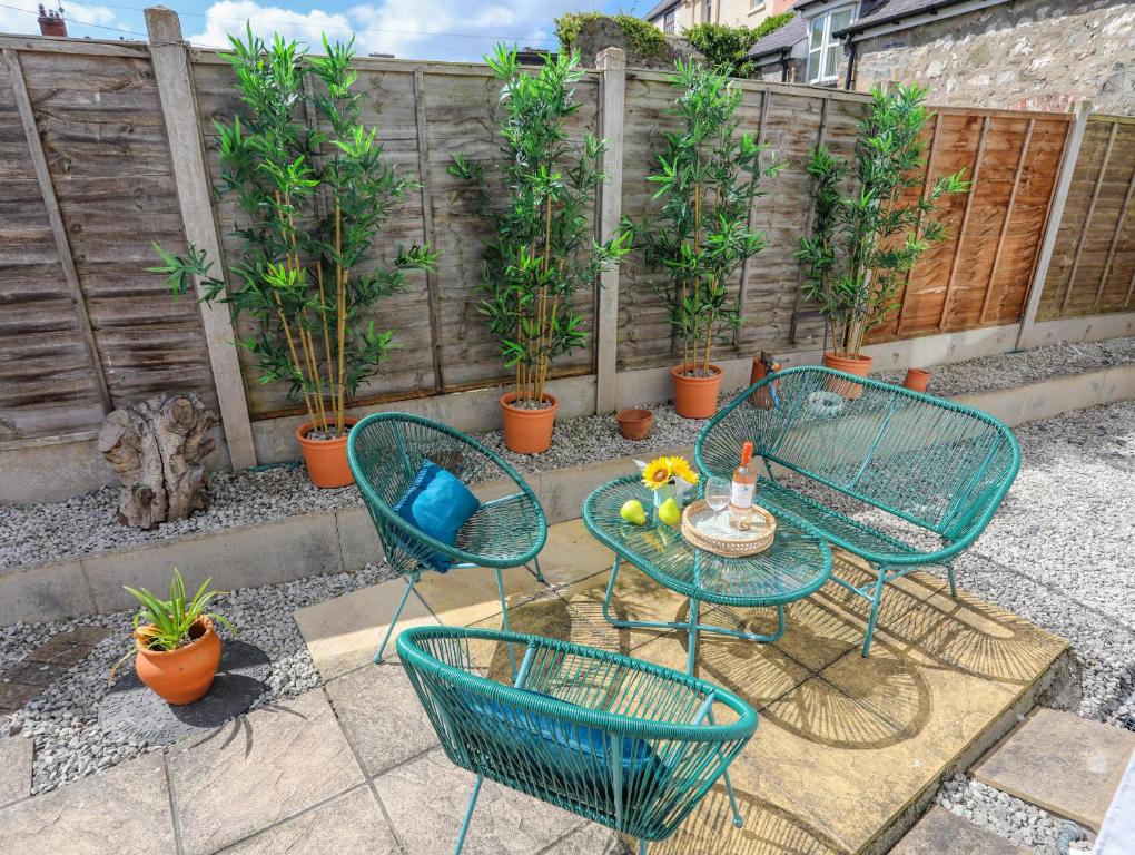 a patio with a table and chairs and plants at 1 Tyn Y Gongl Cottage in Beaumaris