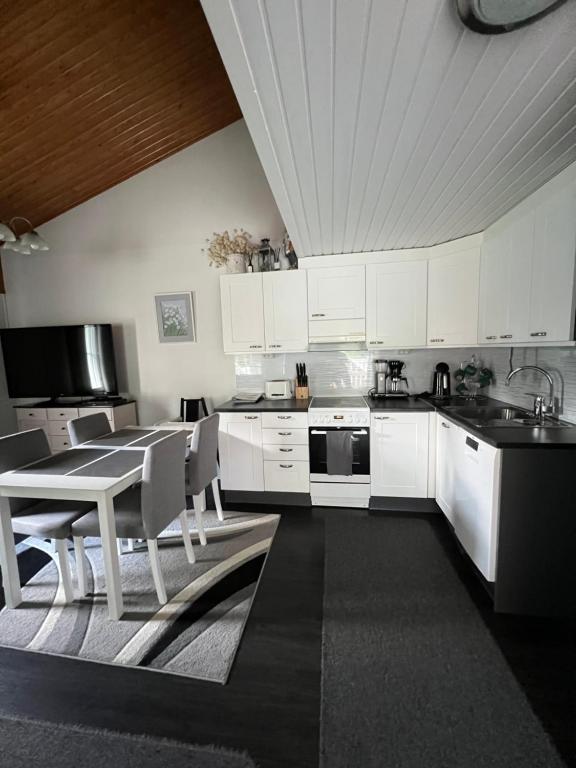 a kitchen with white cabinets and a table and chairs at Pronssi Villa, Vuokatin ytimessä sisältyy Ilmainen pysäköinti, Sauna, etu terassi ja piha alue, Wi-Fi, SmartTV in Vuokatti