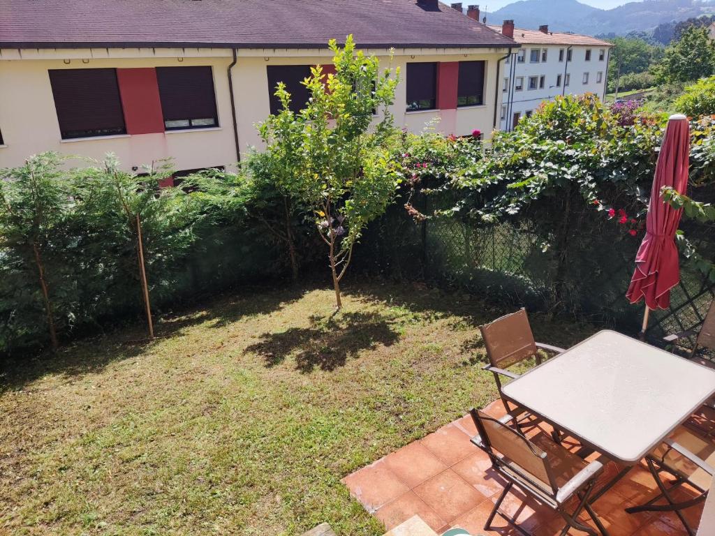 a patio with a table and chairs and a tree at Apartamento Miravalles in Muros de Nalón