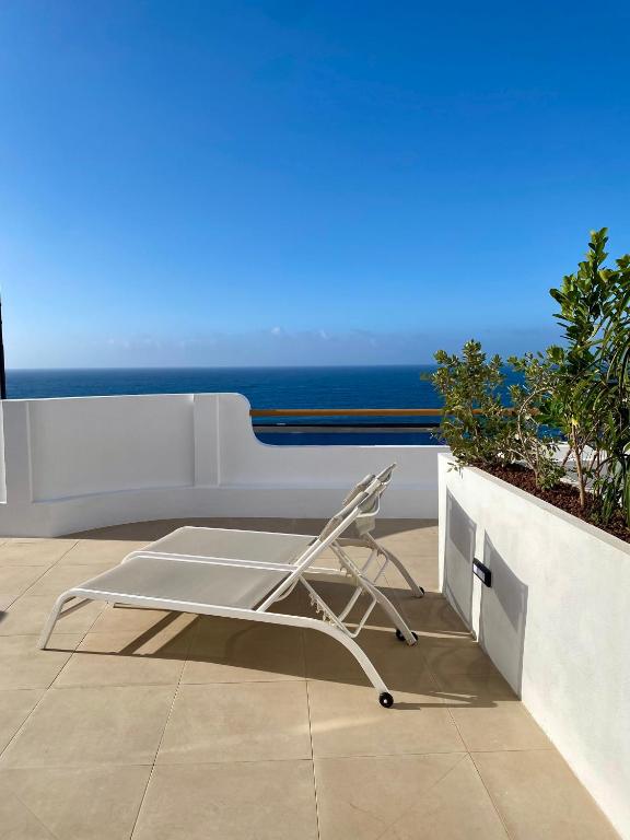 a white chair on a balcony with a view of the ocean at Casa Costa Apartments in Bajamar