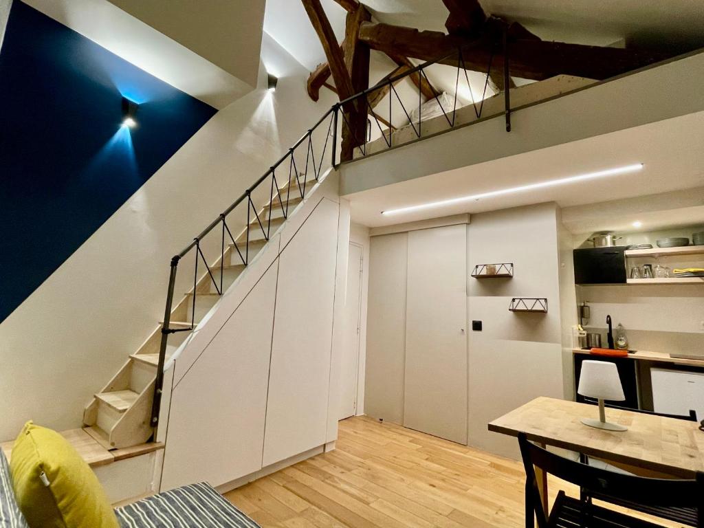 Cet appartement mansardé dispose d'un escalier et d'une table. dans l'établissement Très joli Studio - centre Paris - Le Coeur du Marais, à Paris
