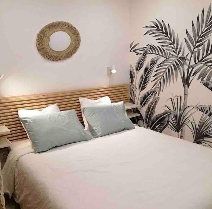 a bedroom with a white bed with a mirror on the wall at Appartement en plein centre à 100m du port in Mèze