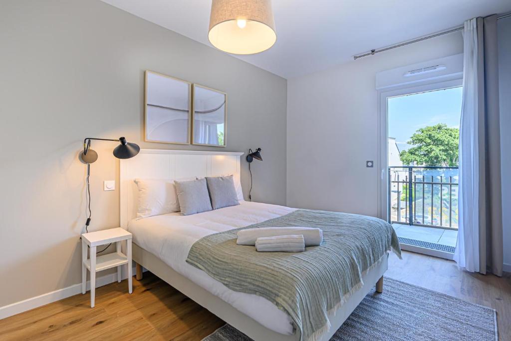 een witte slaapkamer met een bed en een raam bij OVELIA Fouesnant - Les Allées de Kervihan in Fouesnant