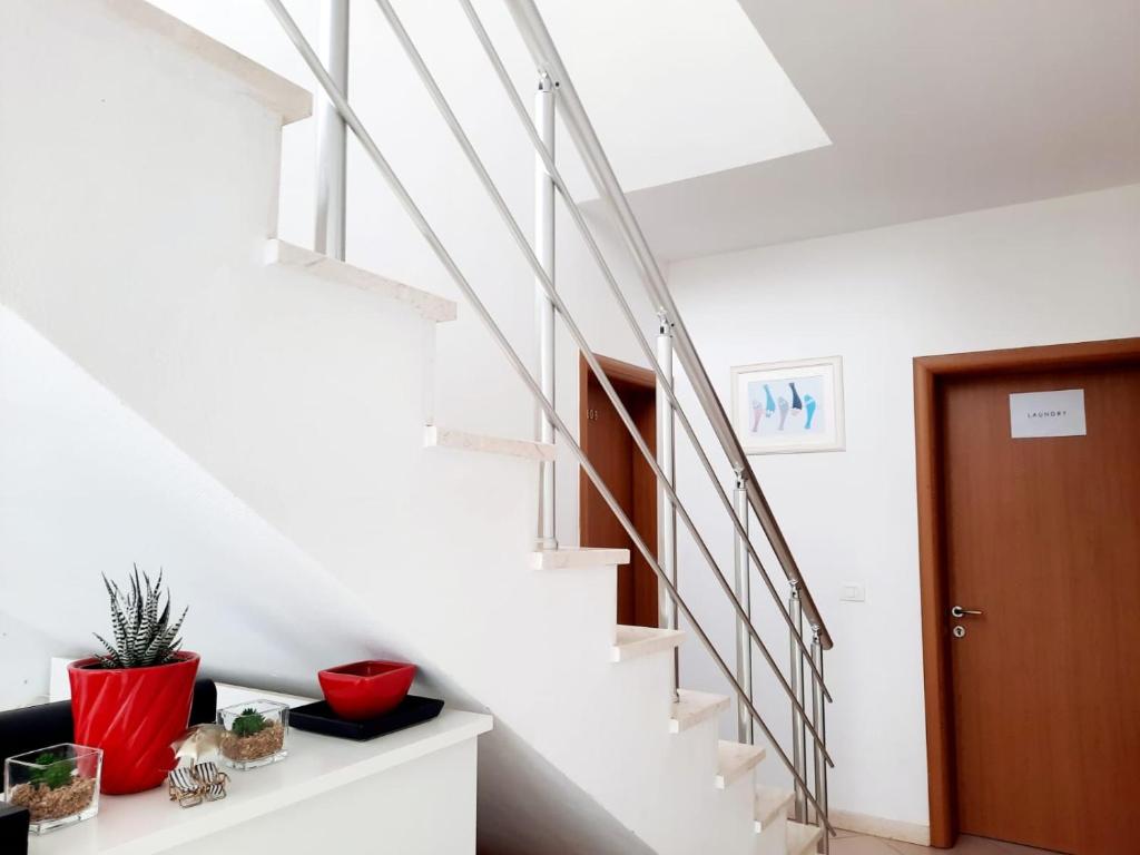 a white staircase in a home with a red plant at Apartments Alavana in Velipojë