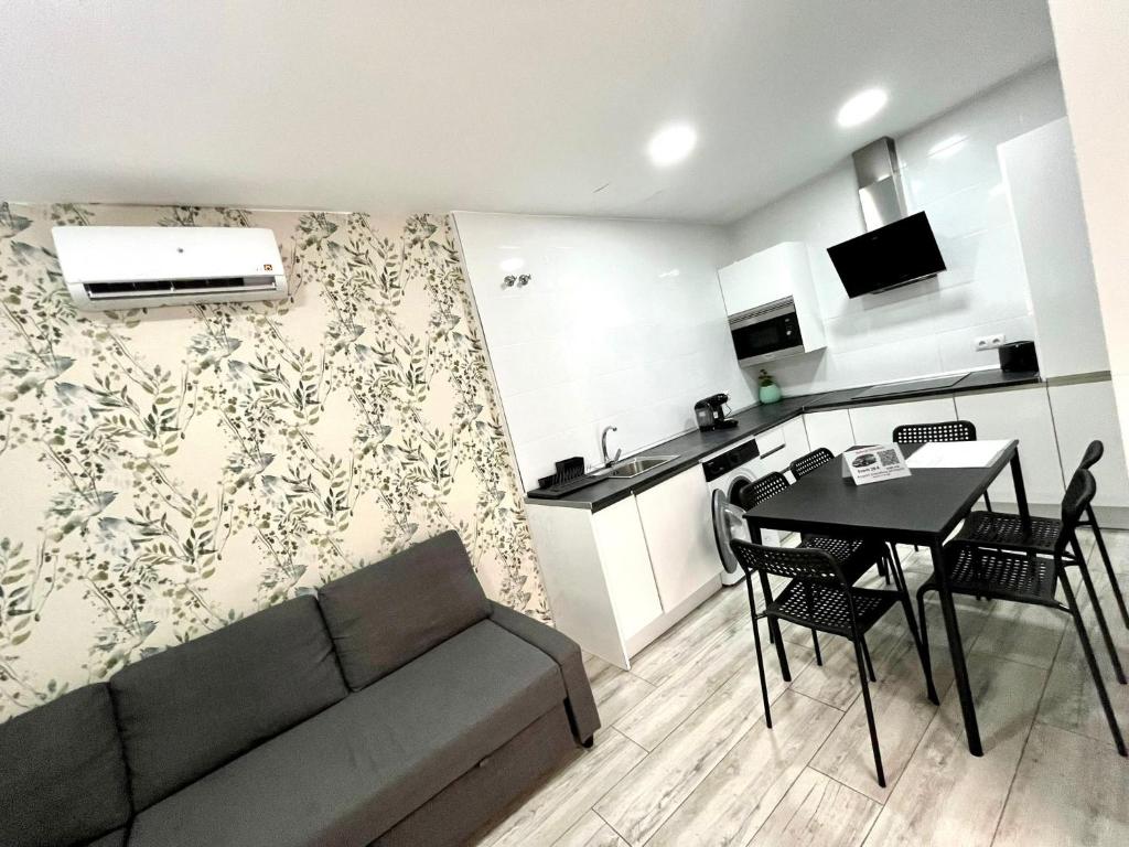 Una sala de estar con un sofá y una mesa y una cocina. en APARTAMENTOS ESTACIONs, en Málaga