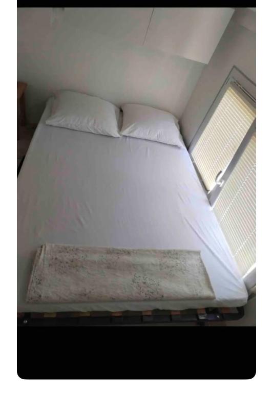 - un lit dans une petite chambre avec 2 fenêtres dans l'établissement Studette indépendant climatisé, à Marseille