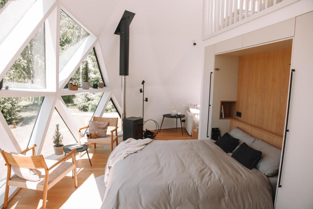 a bedroom with a large bed and large windows at Zaļais Zelts in Katvari