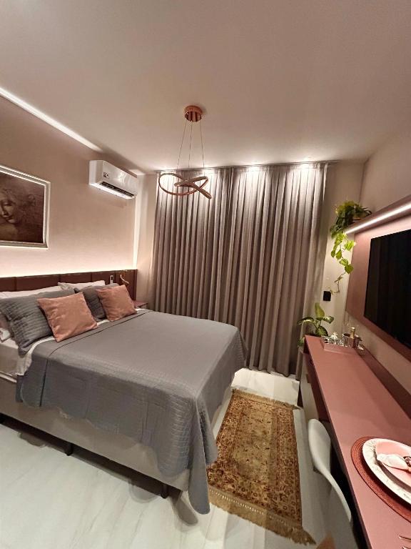 a bedroom with a bed and a desk and a television at Studio Sunset João Pessoa in João Pessoa
