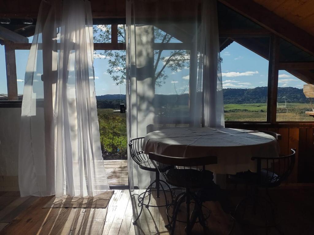 a table and chairs on a porch with a large window at Na'raucária in Cambará