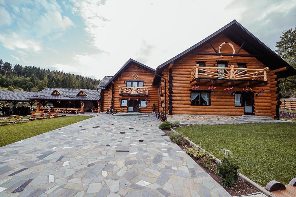 a log cabin with a stone driveway in front of it at Casa din Valea Bucovinei in Valea Moldovei