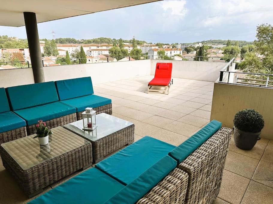 d'une terrasse avec des canapés bleus et une chaise rouge. dans l'établissement L'appart Côté Sud, à Istres
