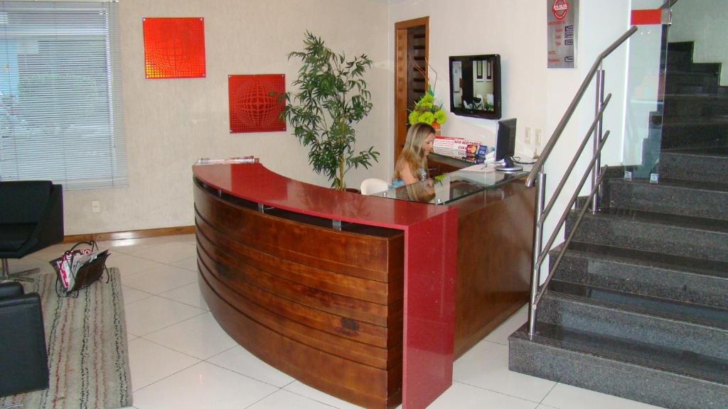 a woman is sitting at a counter in a store at Hotel Elite 1 in Nossa Senhora dos Milagres