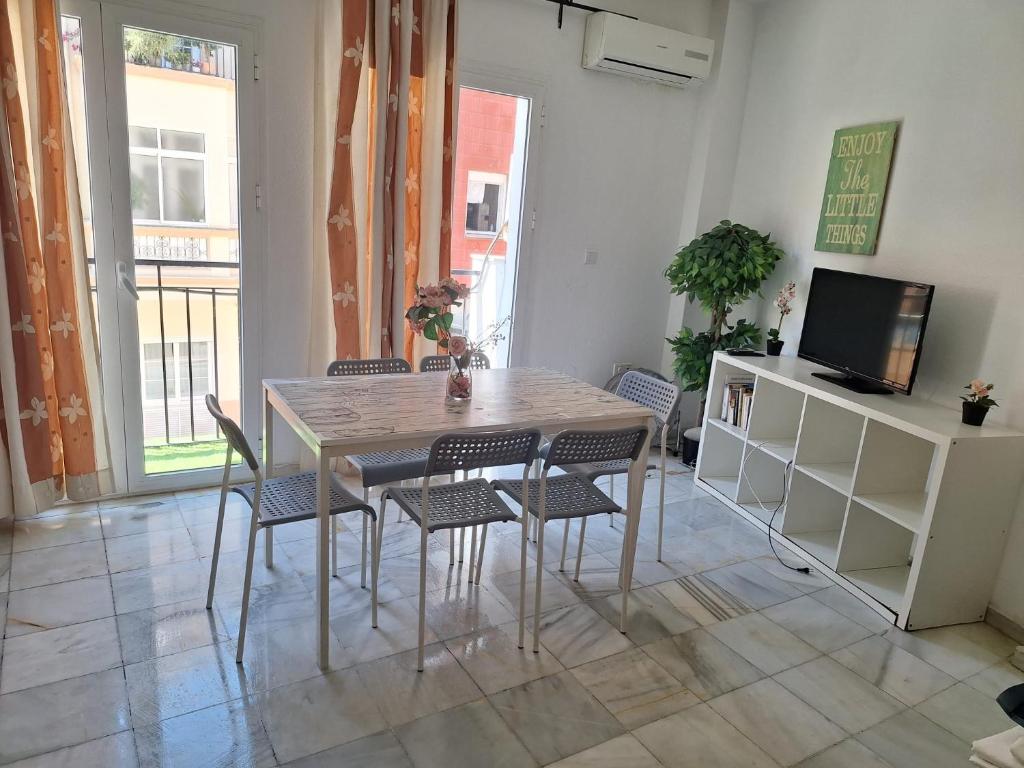 mesa y sillas en una habitación con TV en apartamentos Centro PICASSO, en Málaga