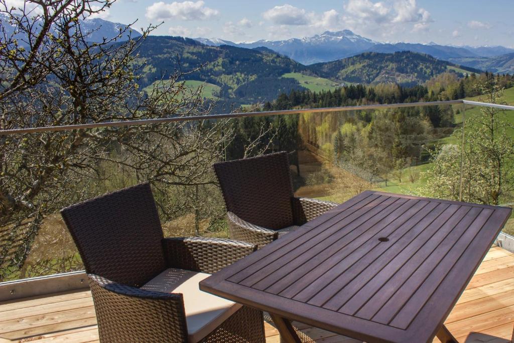a wooden table and chairs on a balcony with mountains at Bauernhof Kronsteiner in Weyregg