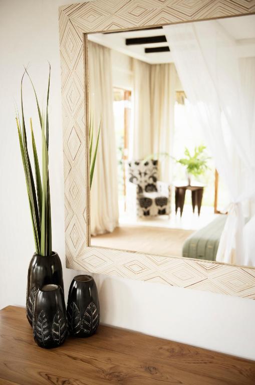 a mirror on a wall with a vase on a table at Qambani Luxury Resort in Michamvi