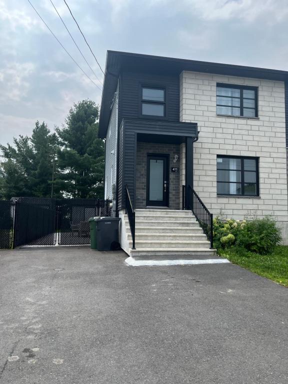 a house with a black fence and a driveway at Luxurya in Drummondville