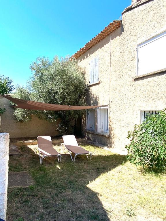 2 chaises et un parasol devant un bâtiment dans l'établissement Soleil d’ocre - Bastide à Roussillon, à Roussillon