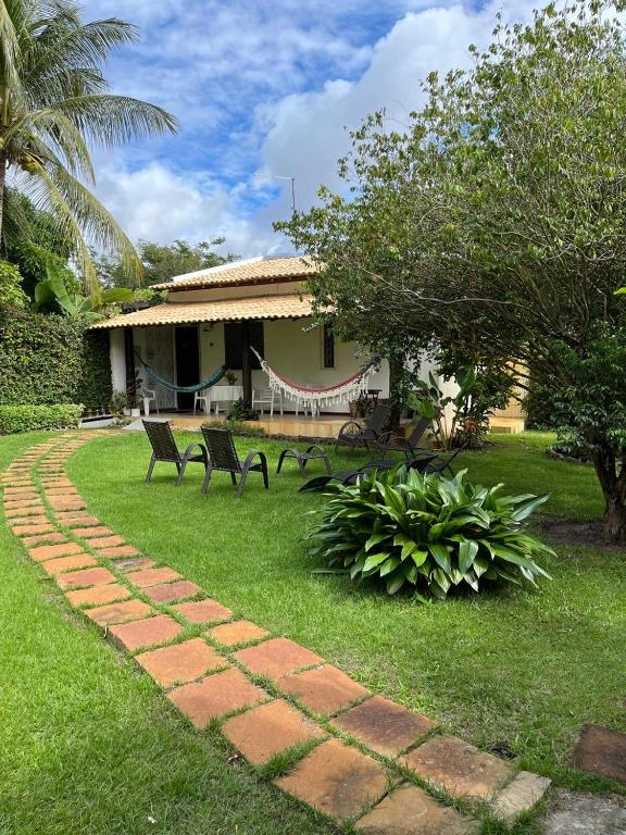 a house with two chairs and a brick path at Cassinha Aconchegante para 2, Varanda com redes, 9 min Praia in Guarajuba