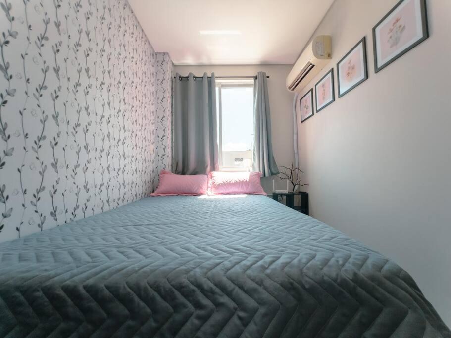 a bedroom with a large bed with a pink blanket at Apartamento Ar Cond Wi-Fi UEM Smart - DG603 in Maringá