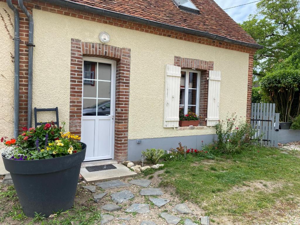 una piccola casa in mattoni con porta bianca e fiori di Petite maison de bourg a Noyers