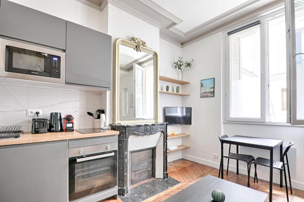 - une cuisine avec des murs blancs, un miroir et une table dans l'établissement Liège - Saint-Lazare, Best location very central, à Paris