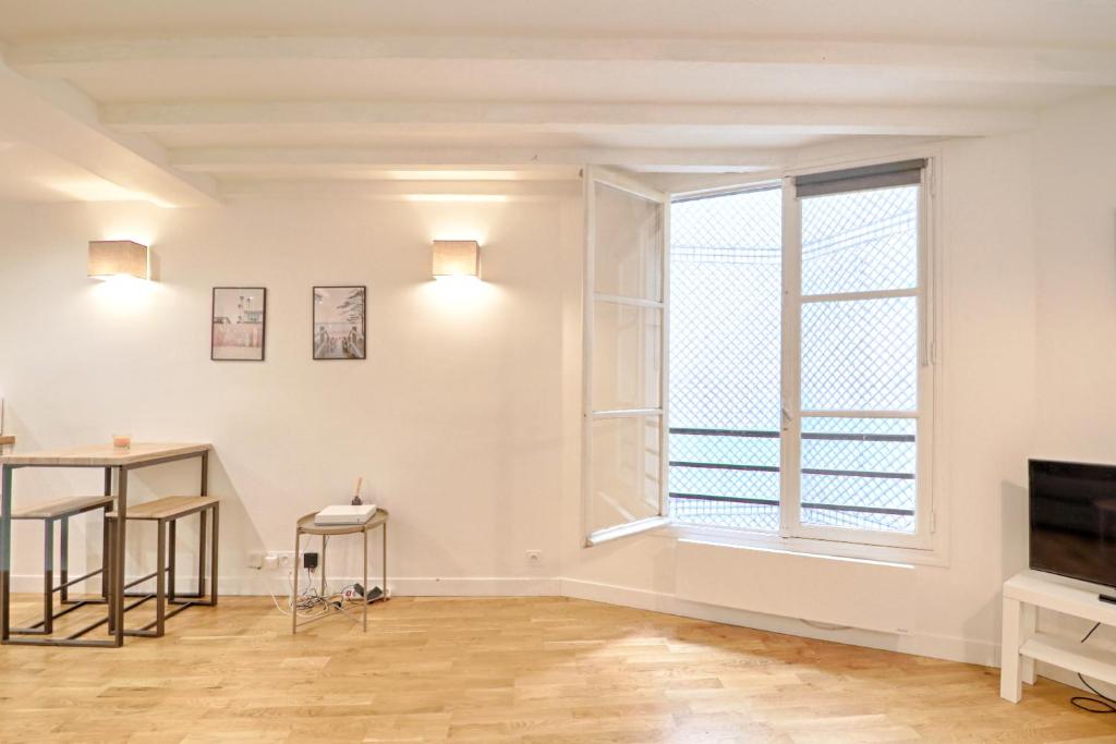 un salon vide avec une fenêtre et une table dans l'établissement Seine - Best localisation - Bail mobilité, à Paris
