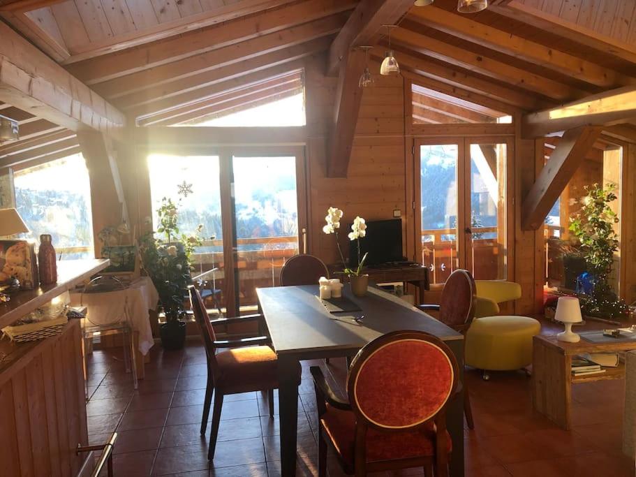une salle à manger avec une table, des chaises et des fenêtres dans l'établissement Appartement de standing en Savoie, à Notre-Dame-de-Bellecombe