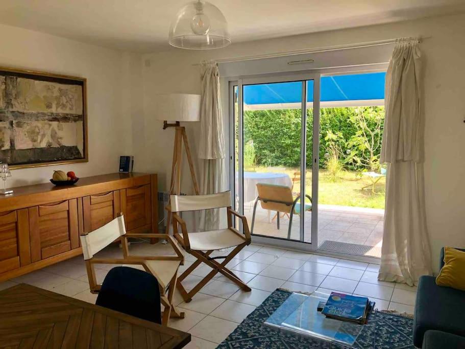ein Wohnzimmer mit einem Stuhl und einer Glasschiebetür in der Unterkunft Maison dans le sud du Morbihan près de la mer in Damgan
