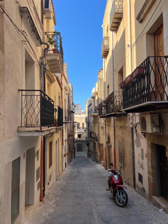 uno scooter rosso parcheggiato in un vicolo tra gli edifici di Casa felicità Sciacca a Sciacca