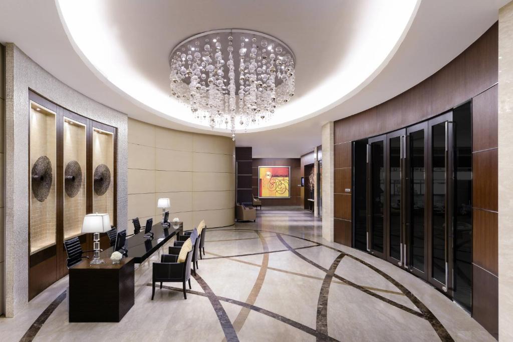 A spacious hotel lobby corridor with reception seating and elevators.