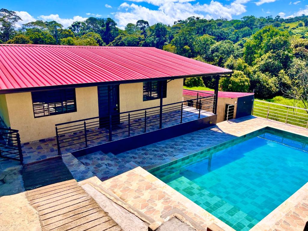 a house with a swimming pool and a red roof at El Diamante - Finca Privada con Piscina Barbosa in Barbosa