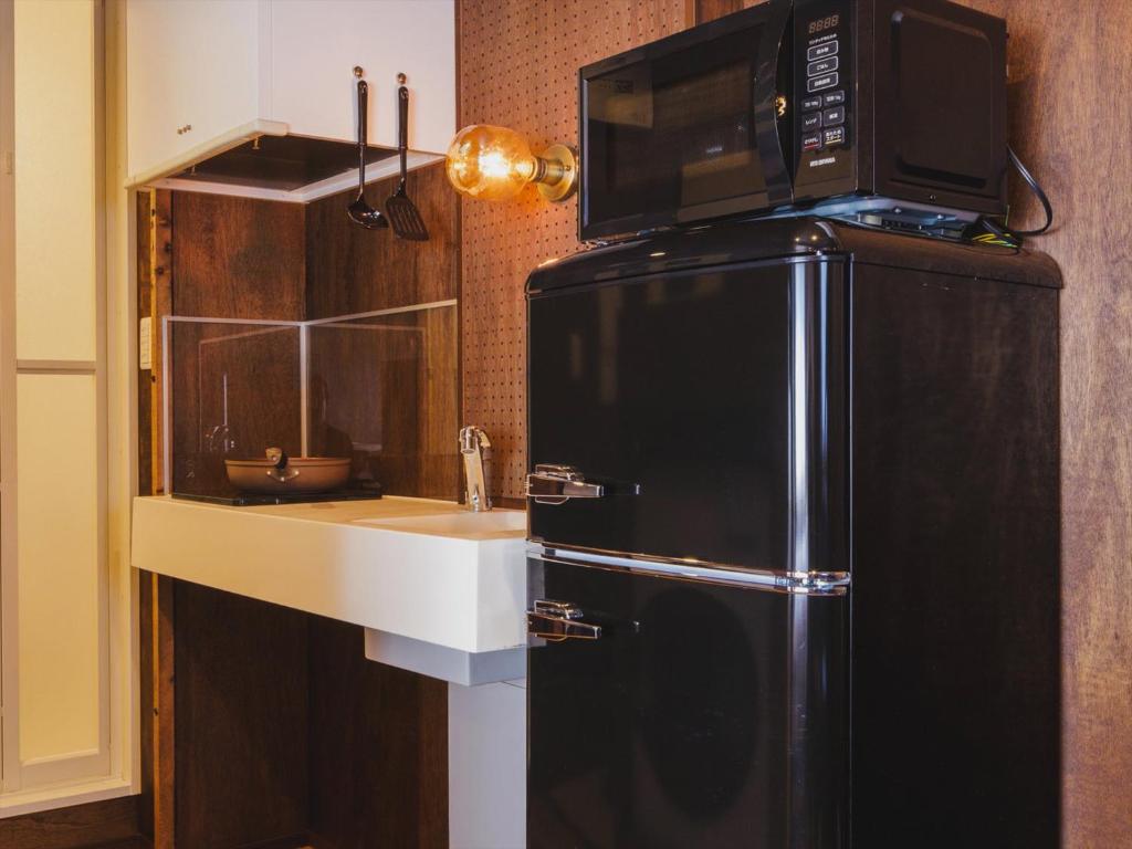a kitchen with a microwave on top of a refrigerator at Seage Torami Coastside in Ichinomiya